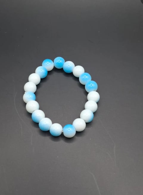 Beaded bracelet with alternating blue and white spherical beads arranged in a circular pattern on gray background