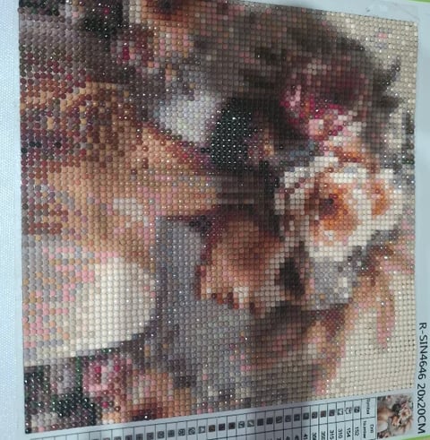 Pixelated portrait made from small circular beads showing warm skin tones and facial features, displayed with measurement ruler at bottom
