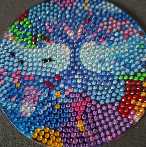 Colorful circular rhinestone emoji art with blue eyes, pink cheeks, and bright gems arranged in a smiling face pattern