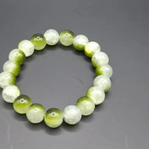 Beaded bracelet with alternating white and yellow-green translucent spheres arranged in a circle on gray background