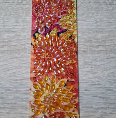 Vertical textile art featuring colorful flower designs in red, gold, and orange with embellished petals on a gray background