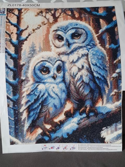 Cross-stitch pattern showing two blue owls perched together on winter branches with snowy background