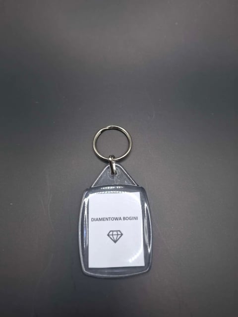 Clear plastic keychain with white label reading Diamentowa Bogini and diamond symbol on gray background