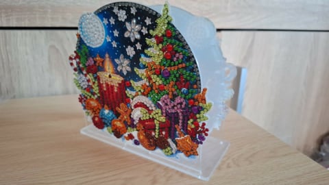 Colorful beaded art display showing a head profile with vibrant rainbow beads on white acrylic stand