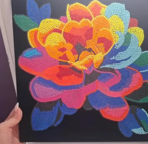 Colorful diamond-painted flower with layered petals in vibrant rainbow colors on black canvas