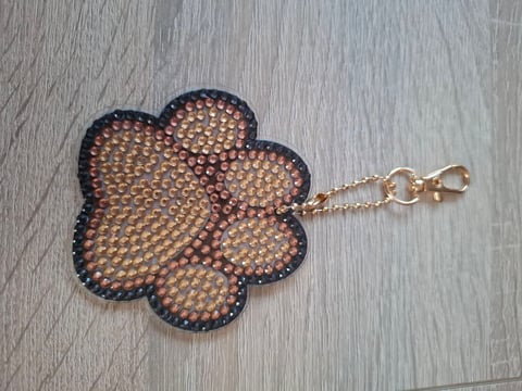 Flower-shaped keychain with bronze and black beaded pattern and gold metal chain clasp