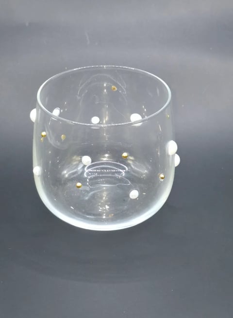 Clear glass vase with white and gold decorative beads suspended inside against gray background