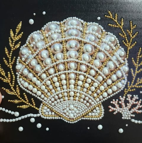 Beaded seashell artwork on black fabric with pearl beads, gold threads, and coral accents