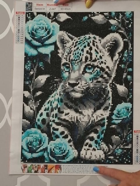 Diamond painting pattern showing a young leopard surrounded by turquoise roses on a black background