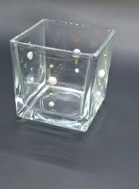Clear glass cube vase with white and gold decorative beads floating inside on gray background
