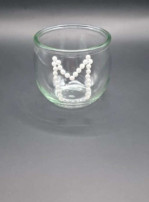 Clear glass votive candle holder with white pearl beaded necklace design inside, displayed against gray background
