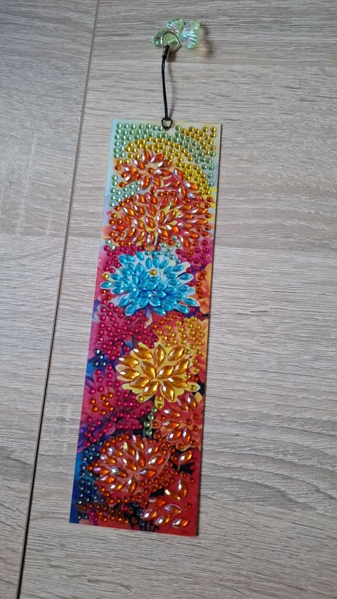 Decorative hanging ornament featuring colorful rhinestone flowers on gradient background with beaded texture
