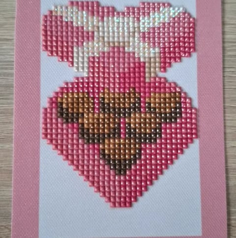 Beaded heart craft with pink and white petals on top heart and brown center on pink-backed bottom heart