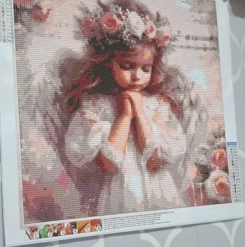 Cross-stitch pattern of a young girl with a flower crown wearing a white dress, printed instruction sheet