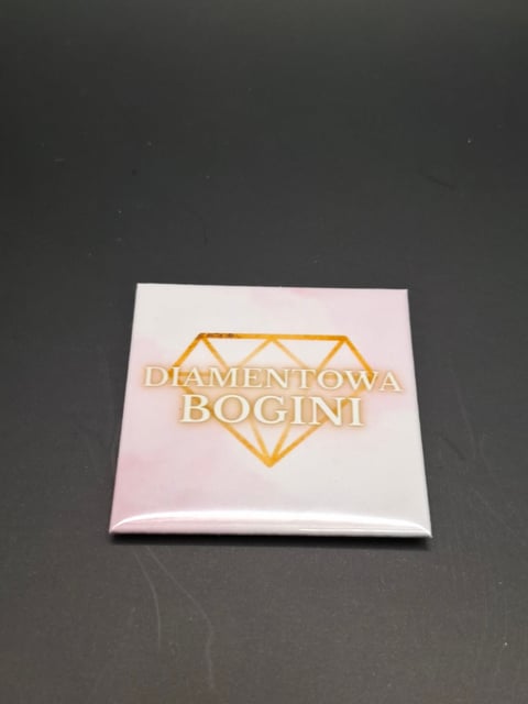 White square box with gold diamond outline and Diamentowa Bogini text on dark surface
