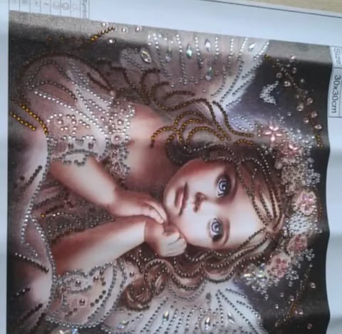 Childs face surrounded by decorative beaded patterns in brown and silver tones on fabric or textile