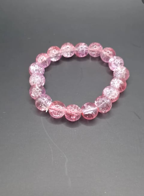 Pink crackle bead bracelet with translucent glass beads arranged in a circular elastic band on gray background