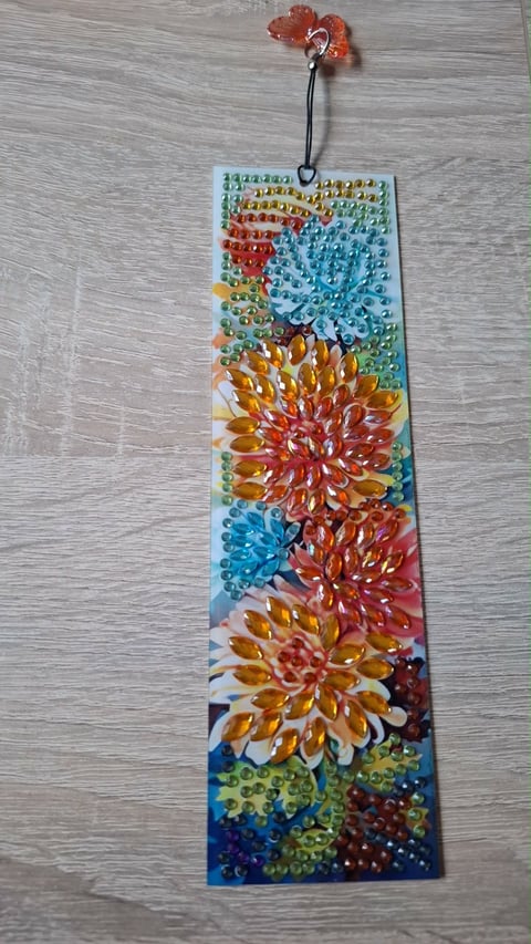 Decorative bookmark with colorful rhinestone flowers and beaded patterns, featuring an orange acrylic charm at the top